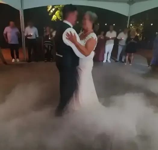 Des mariés qui dansent leur ouverture de bal dans la fumée lourde